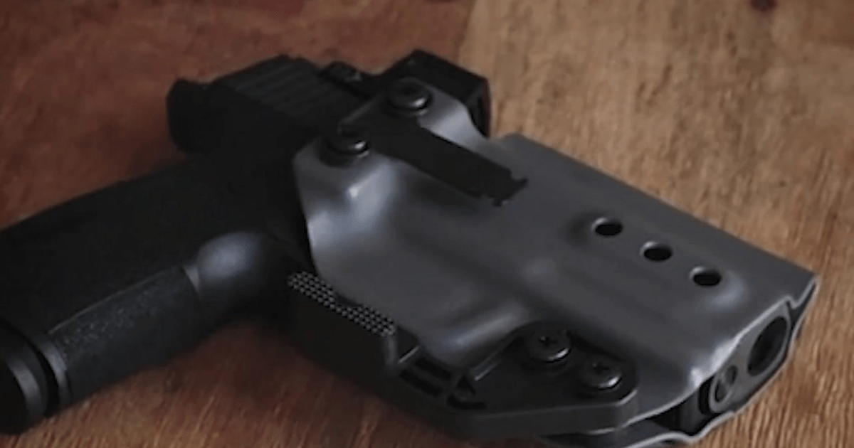 A closeup of a handgun in an Alias system holster by NeoMag.