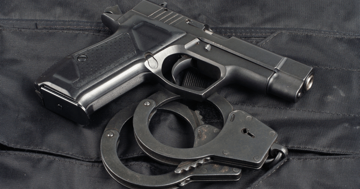 A gun and handcuffs against a black background.