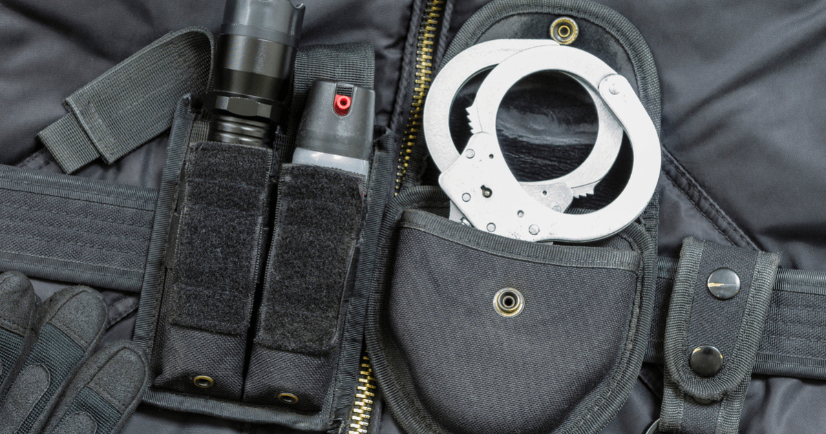 A black duty belt against a black uniform with handcuffs and pepper spray.