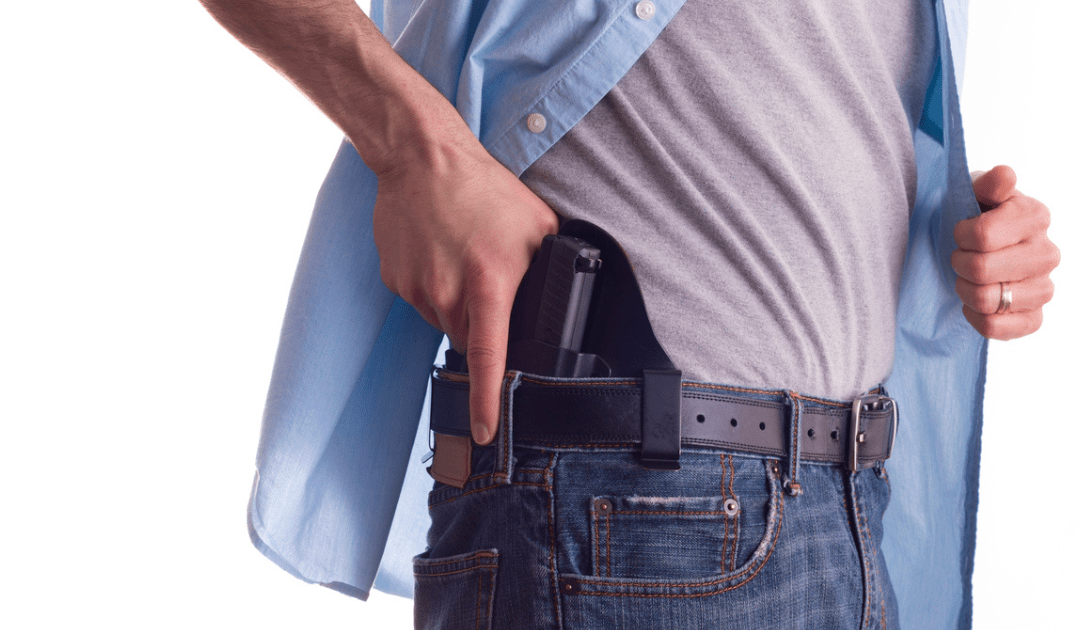 A man wearing a blue shirt carrying a Glock 19.