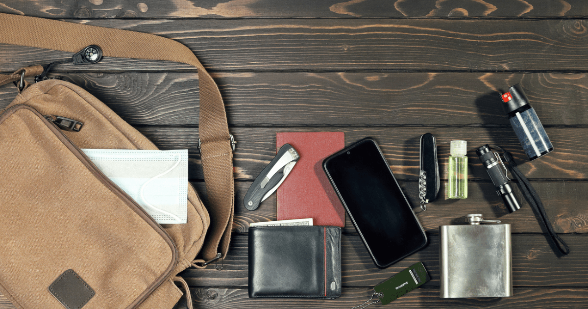 A bag, phone, knife, pen, paper pad, and other items that go into an urban edc bag for city life.