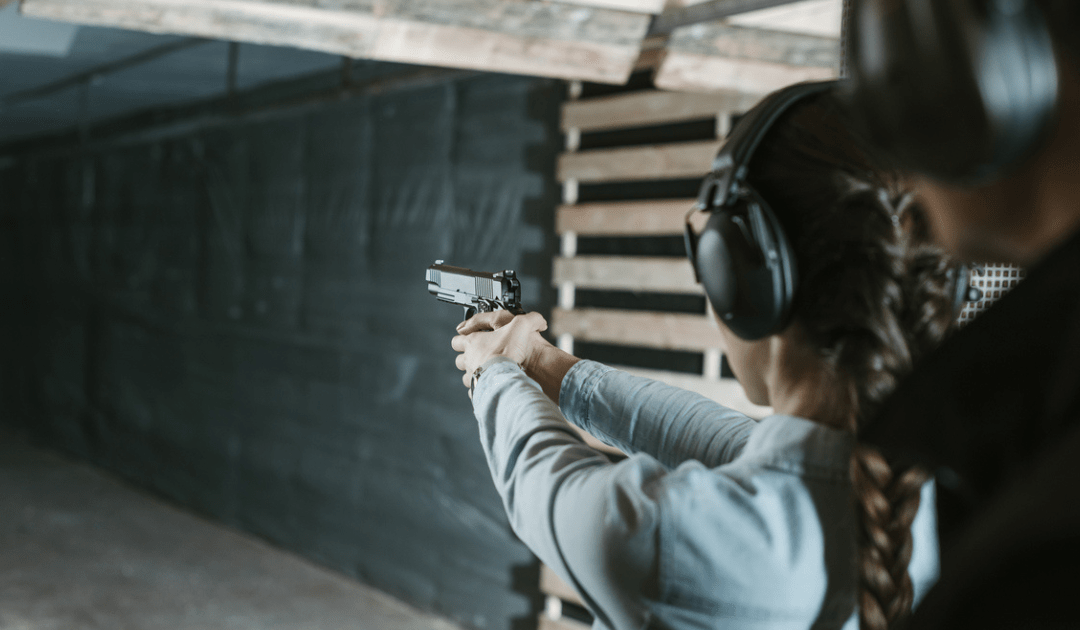 A woman at a shooting range shooting her new handgun.