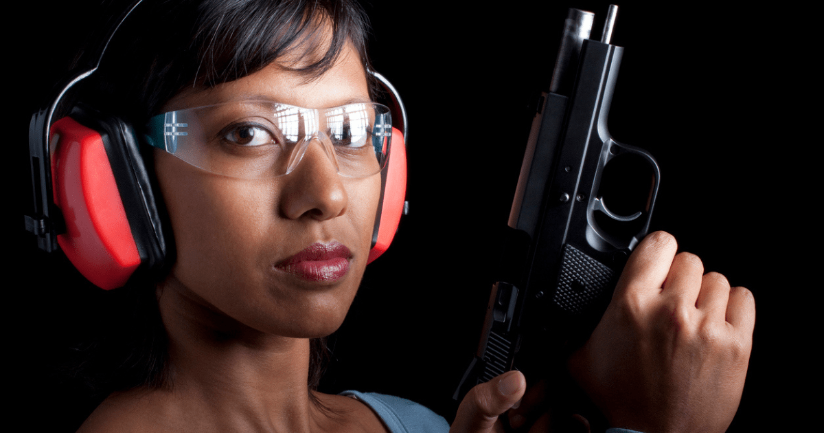 A woman wearing earmuffs, shooting glasses, and holding her new handgun.