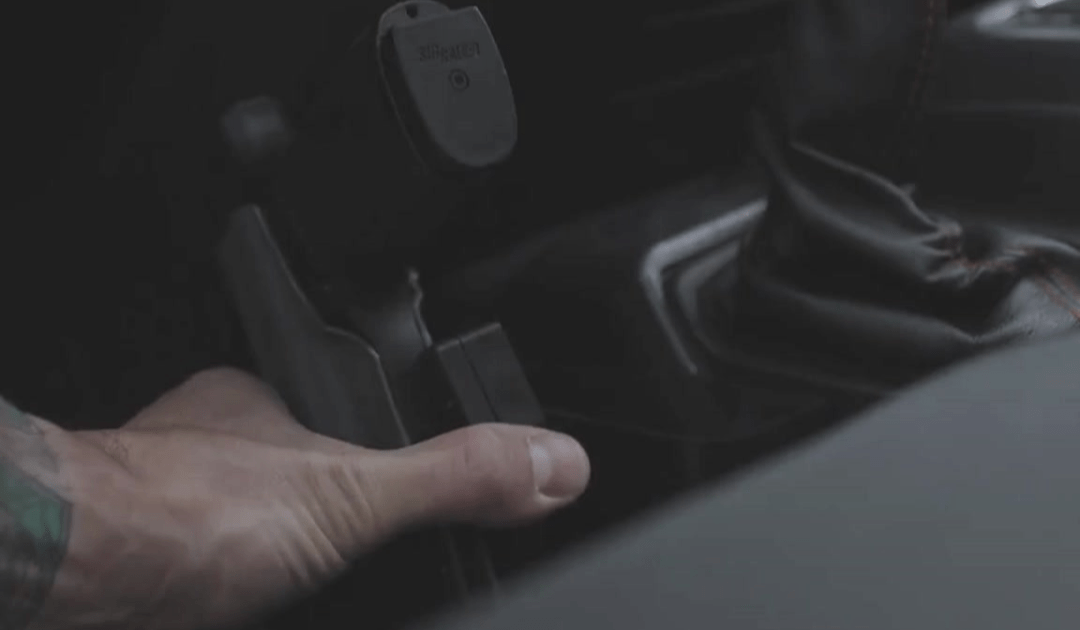 A man putting his gun in his car holster using his Alias Hardmount Receiver.