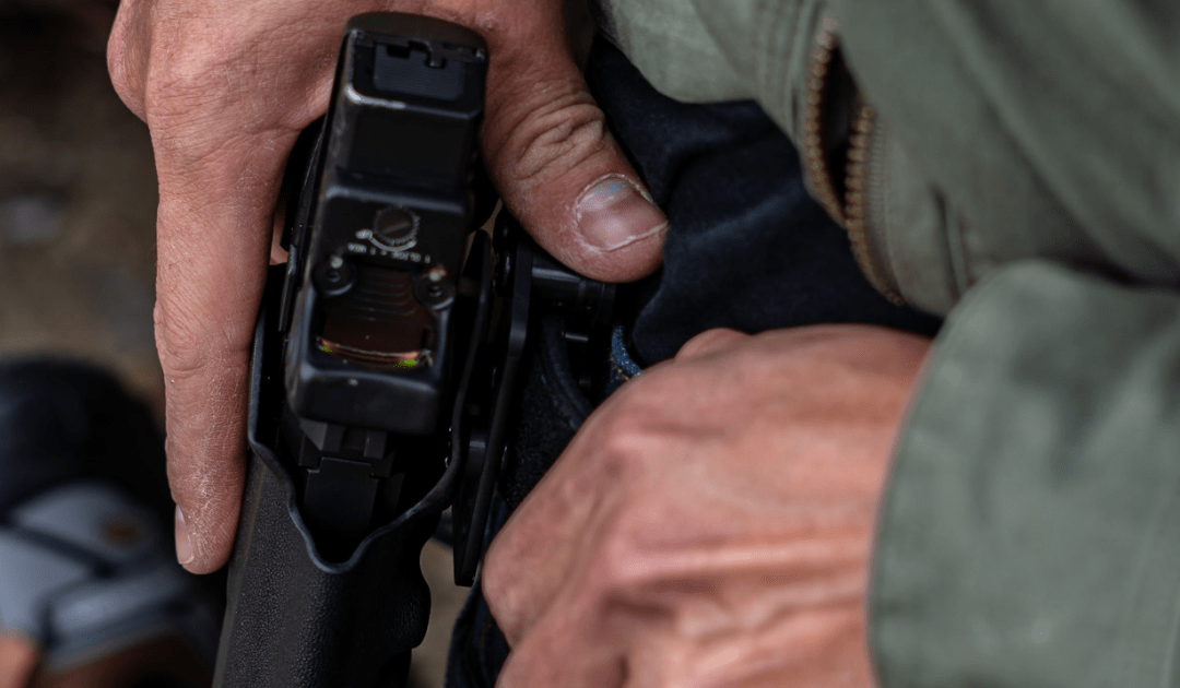 A man secures his holster to his belt using an Alias Receiver with brackets.