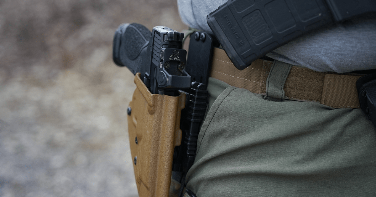 A gun in a brown holster attached to the Alias Belt with an Alias Receiver.