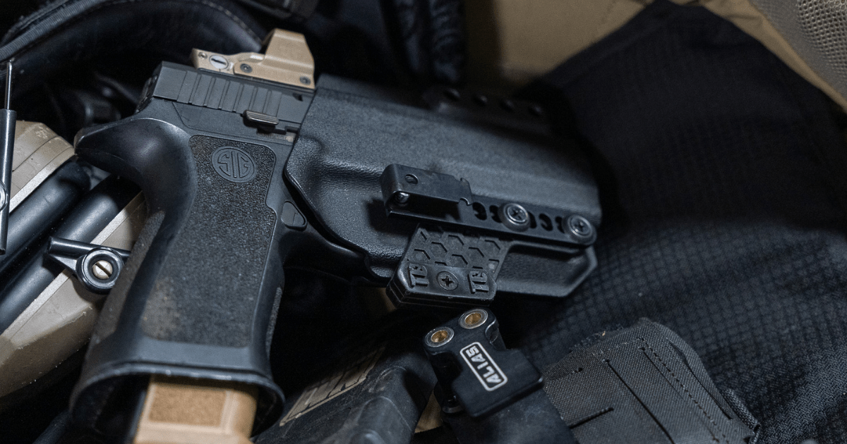 A gun in a holster laying on a table with other gear.