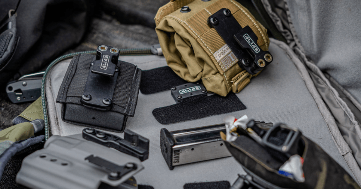 Various gun accessories with NeoMag's Alias Belt System receivers and adapters attached laying gun carrying case.