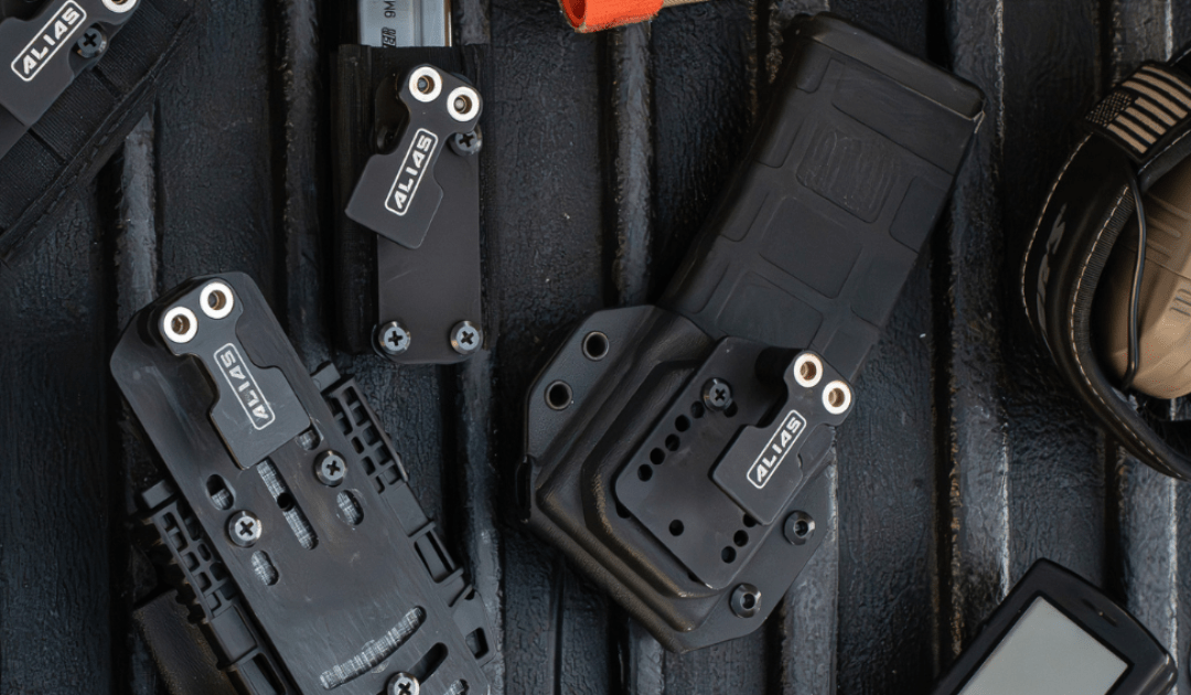 Various gun accessories with Alias Receivers attached laying in a black truck bed.