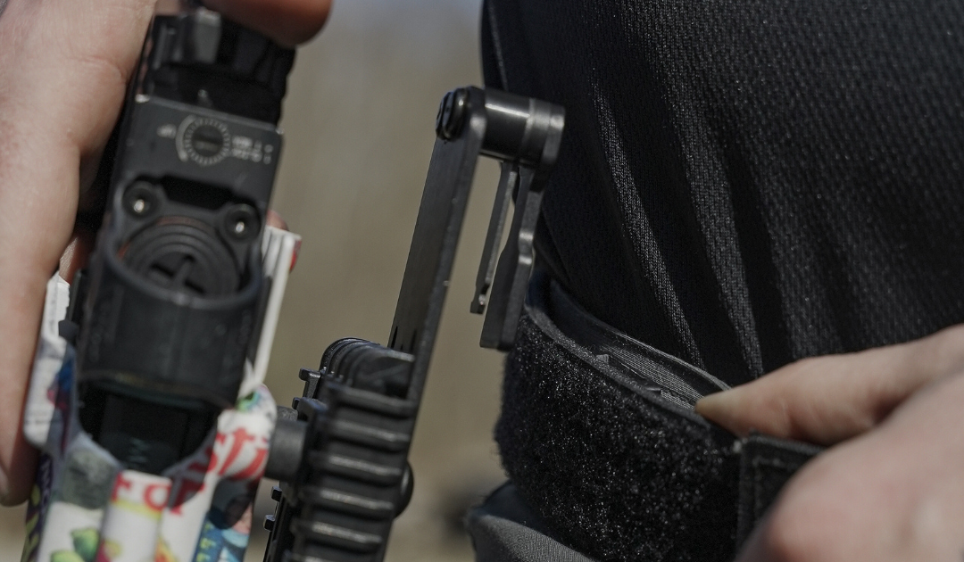 A person putting his holster on his Alias Belt using an Alias OWB Drop Adapter.