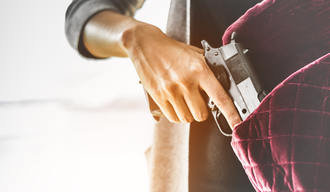 A woman puts her gun into her EDC bag.