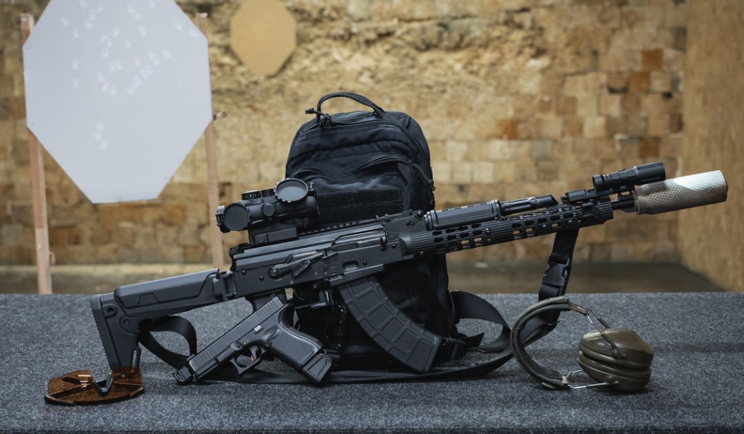 A rifle next to a range bag and other gear in a shooting range.